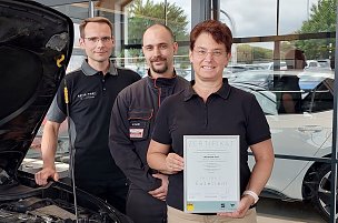 Drei Mitarbeiter stehen nebeneinander und halten ein Zertifikat hoch