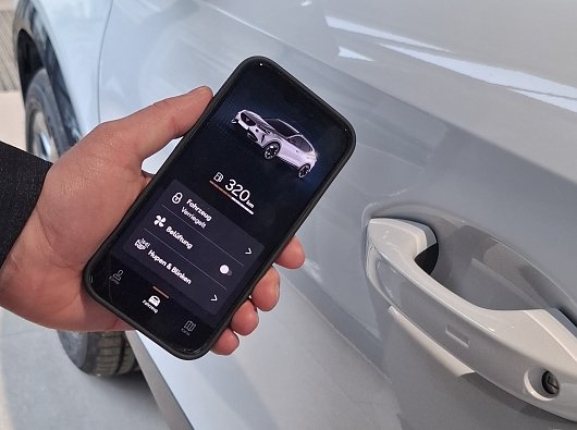 Smartphone mit Connect App vor einem Auto (Ratio Mobil)